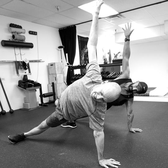 Trainer performing a dynamic side plank movement in the Flow State Fitness studio